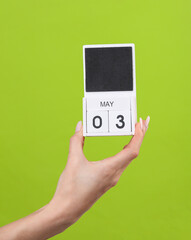 Block calendar with date may 03 in female hand on green background