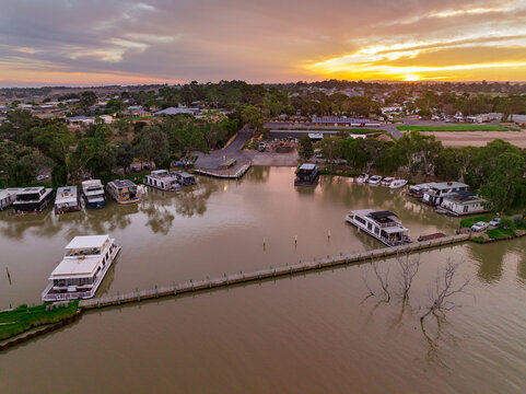 Aerial view of a house boat marina on a river with a sunset behind