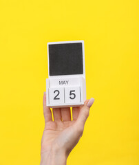 Block calendar with date may 25 in female hand on yellow background