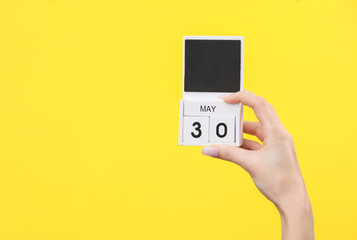 Block calendar with date may 30 in female hand on yellow background