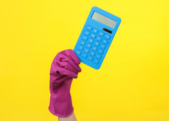 Hand in purple rubber cleaning glove holding calculator on a yellow background. House cleaning and...