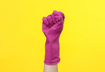 Feminism. Women's power. Fist in a rubber glove for cleaning on yellow background