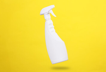 Mockup of a white bottle of window cleaner spray levitating on a yellow background with a shadow....