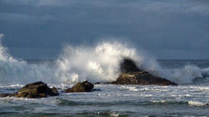 Fototapeta na wymiar Waves breaking on a rock just off the beach in Zipolite, Mexico