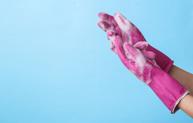 Hands in rubber gloves with foam on blue background. Copy space