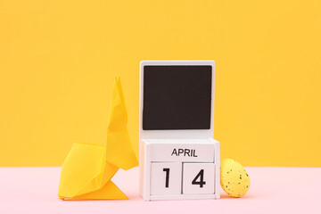 Happy easter. Calendar with date april 14 and easter  rabbit with eggs on yellow background
