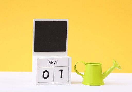 Calendar with date may 01 with miniature watering can on yellow background