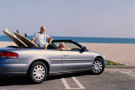 Couple in Convertible Car with Surfboards
