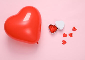 Red heart-shaped air balloon and gift box with many hearts on a pink background. Valentine's Day