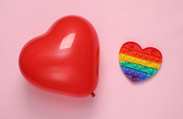 Red heart-shaped air balloon with pop it antistress toy on a pink background. Valentine's Day