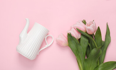 Bouquet of pink tulips with a ceramic teapot on a pink background. Top view