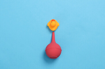 Enema with rubber duck on blue background. Creative layout