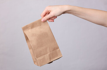 Female hand holding craft product pack on gray background