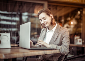 Young woman using laptop while sitting at a table in an outdoor cafe