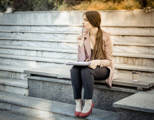 Pensive business woman sitting on a bench in the park