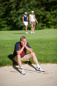 Man Sitting by Sand Trap on Golf Course
