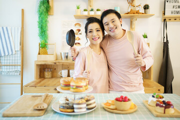 Happy young couple cooks a breakfast together in kitchen, romantic Asian young couple cooking a breakfast in the morning.