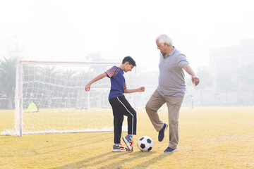 Family playing football outdoors and boy attacking his grandfather.