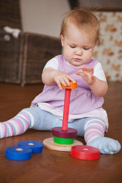 Baby Girl Sitting on Floor Playing with Toy