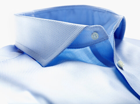 Detail of collar of blue shirt on white background in studio