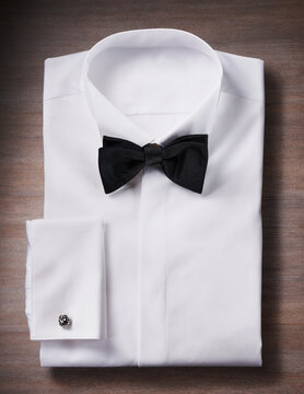 White, tuxedo shirt with a bow tie and cuff link, studio shot on wooden background