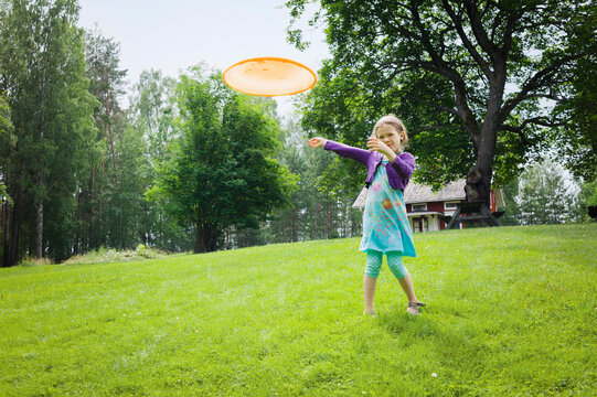 Young girl playing with a frisbee in the garden, Sweden