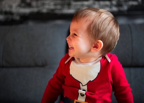 Portrait of cute little boy in Santa clothes sitting on a sofa