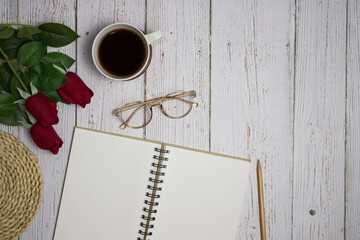 White notebook with glasses and coffee on wooden table with copy space.