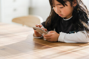 スマートフォンを見る幼い日本人の女の子