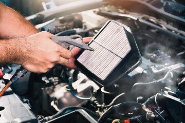 Auto mechanic is blowing dust and cleaning a car air filter with air blow gun, car maintenance...