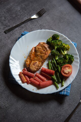 Grilled chicken and vegetables saute in a plate. View from top, selective focus.