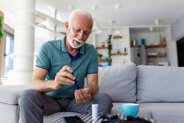 Mature man testing for high blood sugar. Man holding device for measuring blood sugar, doing blood...