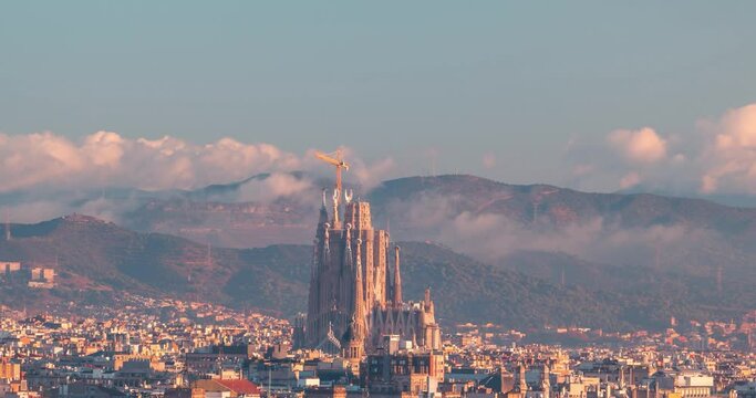 Barcelona Sagrada Familia still under construction detail shot  timelapse during  early winter morning with low clouds in the backgroud aerial views of the city in Catalonia,  Spain.