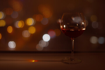red wine glass on bokeh lights of night city life background. festive mood bright abstraction background