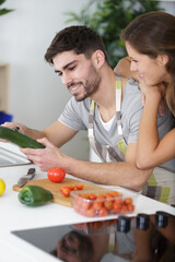happy man and woman cooking vegetables in kitchen