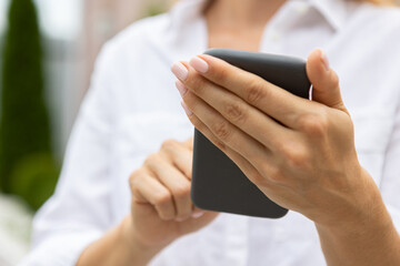 female hands hold a modern mobile phone on the street..education, modern app, shopping order, work online
