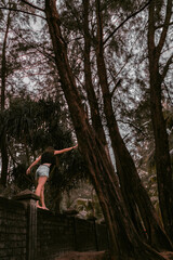 A girl walks under palm trees. Dark photo processing