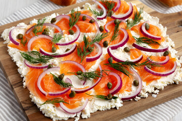 Homemade Cream Cheese Lox Bagel Board with Salmon on a white wooden surface, low angle view. Close-up.