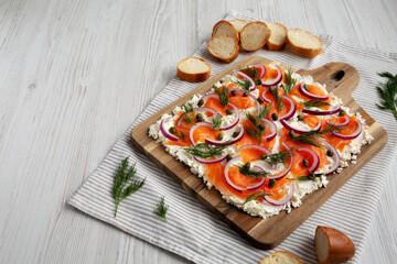 Homemade Cream Cheese Lox Bagel Board with Salmon on a white wooden surface, low angle view. Space for text.
