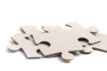 Close-up on jigsaw puzzle pieces, blank white paper jigsaw puzzle elements linked together and separate.