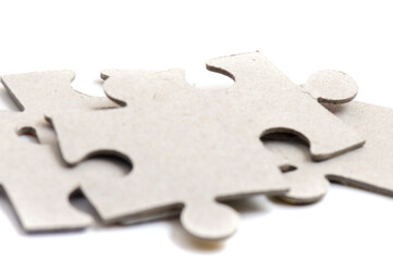 Close-up on jigsaw puzzle pieces, blank white paper jigsaw puzzle elements linked together and separate.