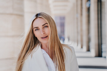 Portrait of focused blonde female entrepreneur with candid smile, Italian young businesswoman happy to be successful, looks at camera. Cheerful caucasian lawyer satisfied by her life. Business people.