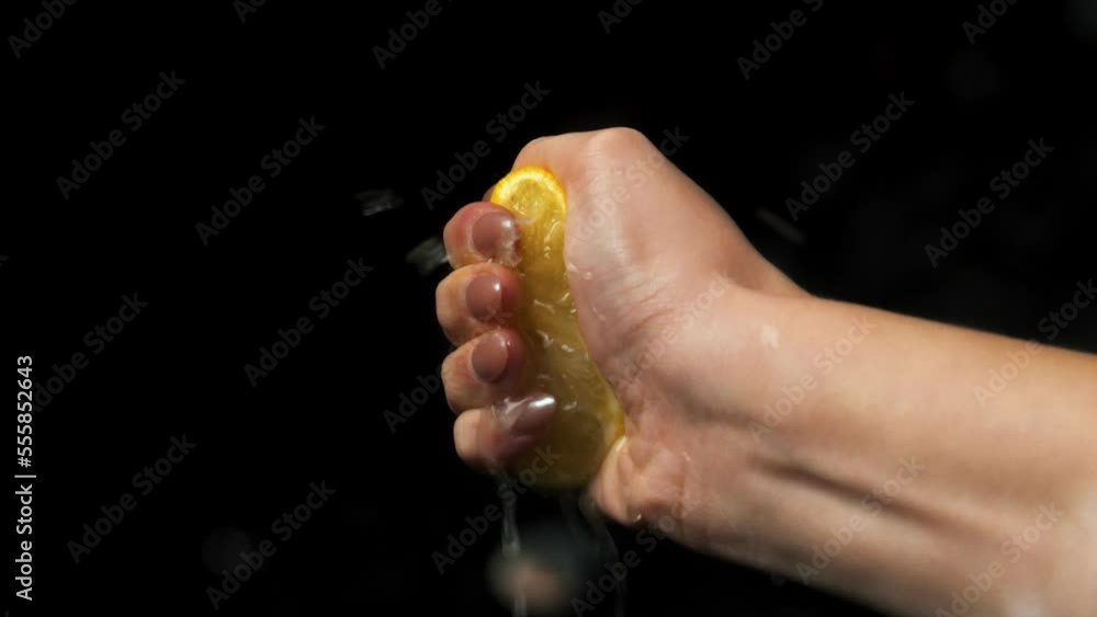 Poster static slow motion shot of a woman's hand with a lemon being squeezed in her hand while the lemon ju