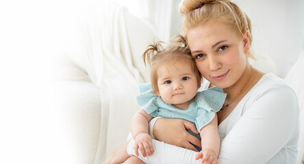 Fototapeta na wymiar Portrait of young tired Mother and baby girl looking at camera home. Child care, domestic life routine, healthy lifestyle. Exhausted woman take care about child and household duties. Copy space