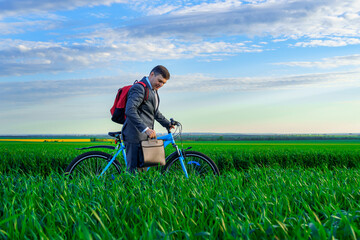 a businessman rides a bicycle with a backpack and a briefcase on a green grassy field, dressed in a business suit, beautiful nature in spring, freelance business concept