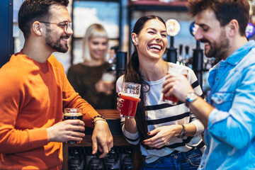 Smiling young friends drinking craft beer in pub