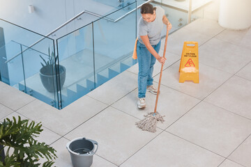Cleaning service, office building or woman mopping floor with warning sign for job safety compliance. Bucket, bacteria or girl cleaner working on wet floor for dirty, messy or dusty tiles on ground