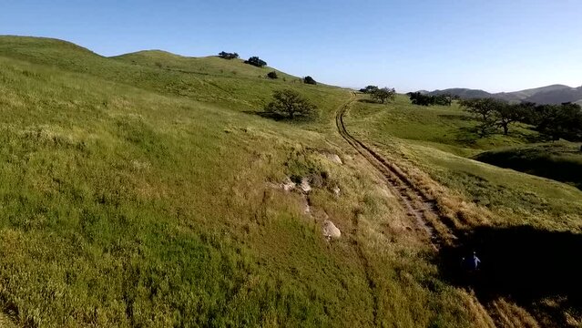 ATV Speeding Through Muddy Trail Through Green Rolling Hills