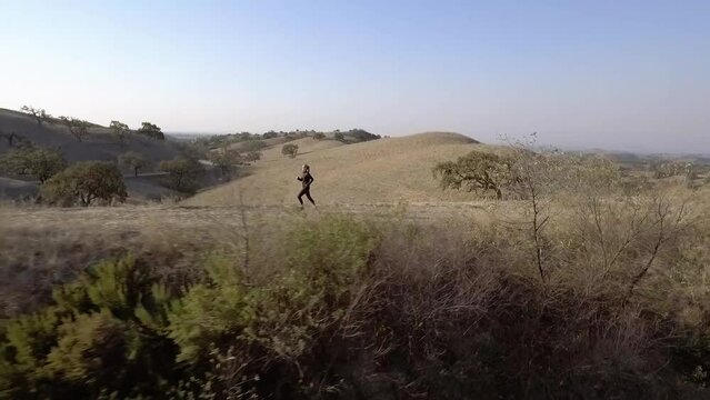 Aerial of Woman Running Past a Lake During Golden Hour