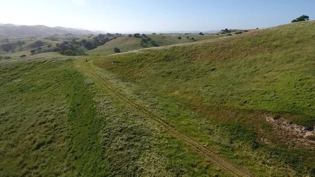 Aerial of ATV Speeding by Green Rolling Hills in Santa Barbara County
